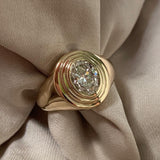 GOLD SIGNET RING WITH AN OVAL DIAMOND AND CONCENTRIC STEPS AROUND THE DIAMOND