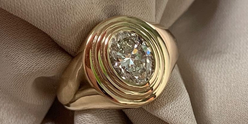 GOLD SIGNET RING WITH AN OVAL DIAMOND AND CONCENTRIC STEPS AROUND THE DIAMOND